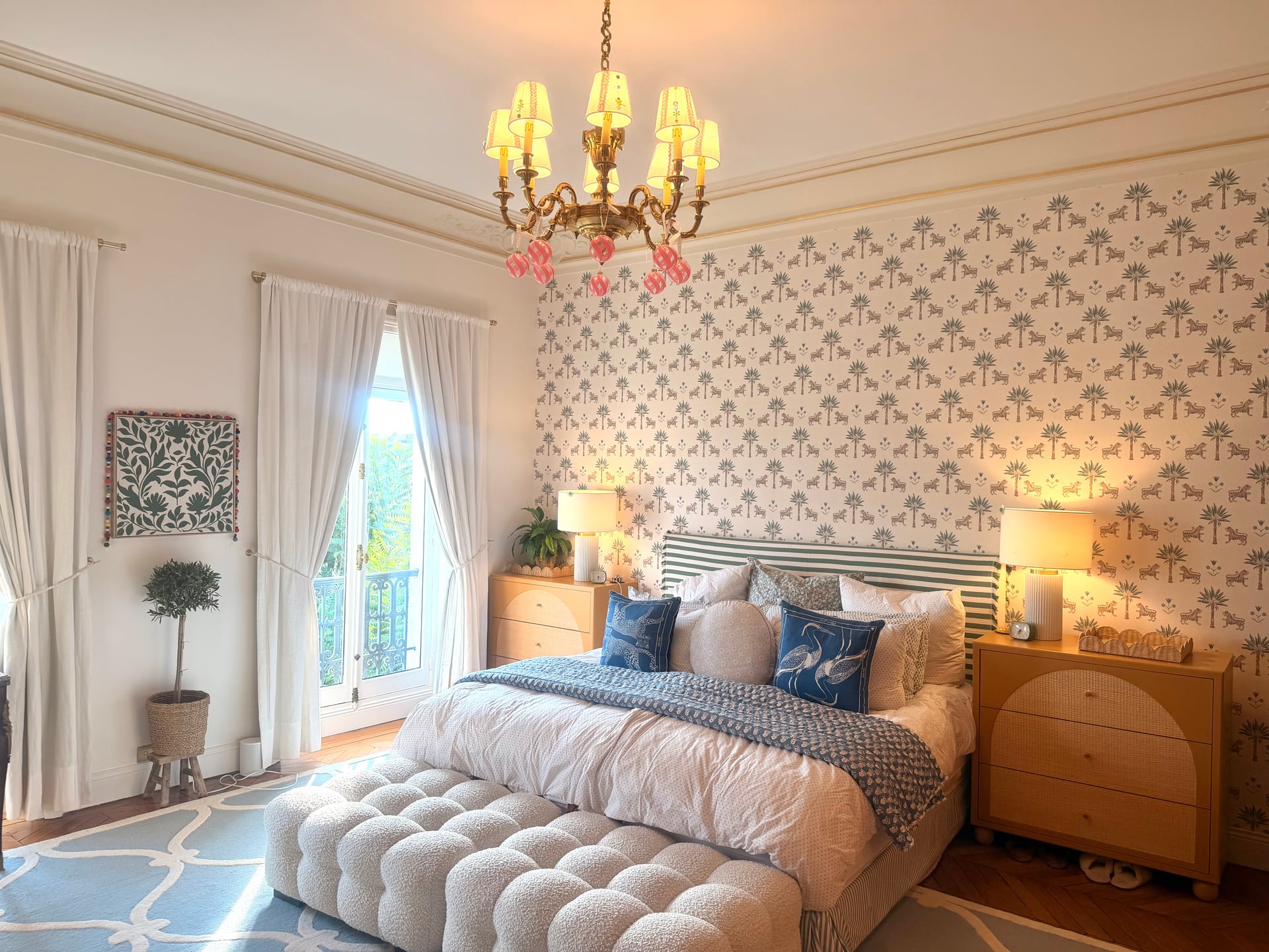 Master bed by the tall window and topiary, lamps warm